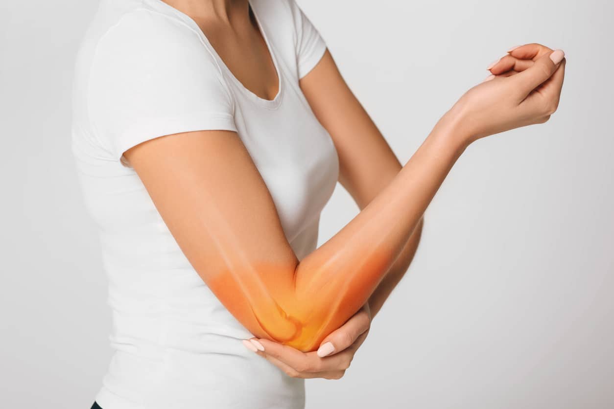 commonelbowinjuries Person in white shirt holding right elbow with left hand, orange-yellow glow indicating joint pain or inflammation. Let me know if you'd like a version tailored for medical education, wellness platforms, or orthopedic product listings.