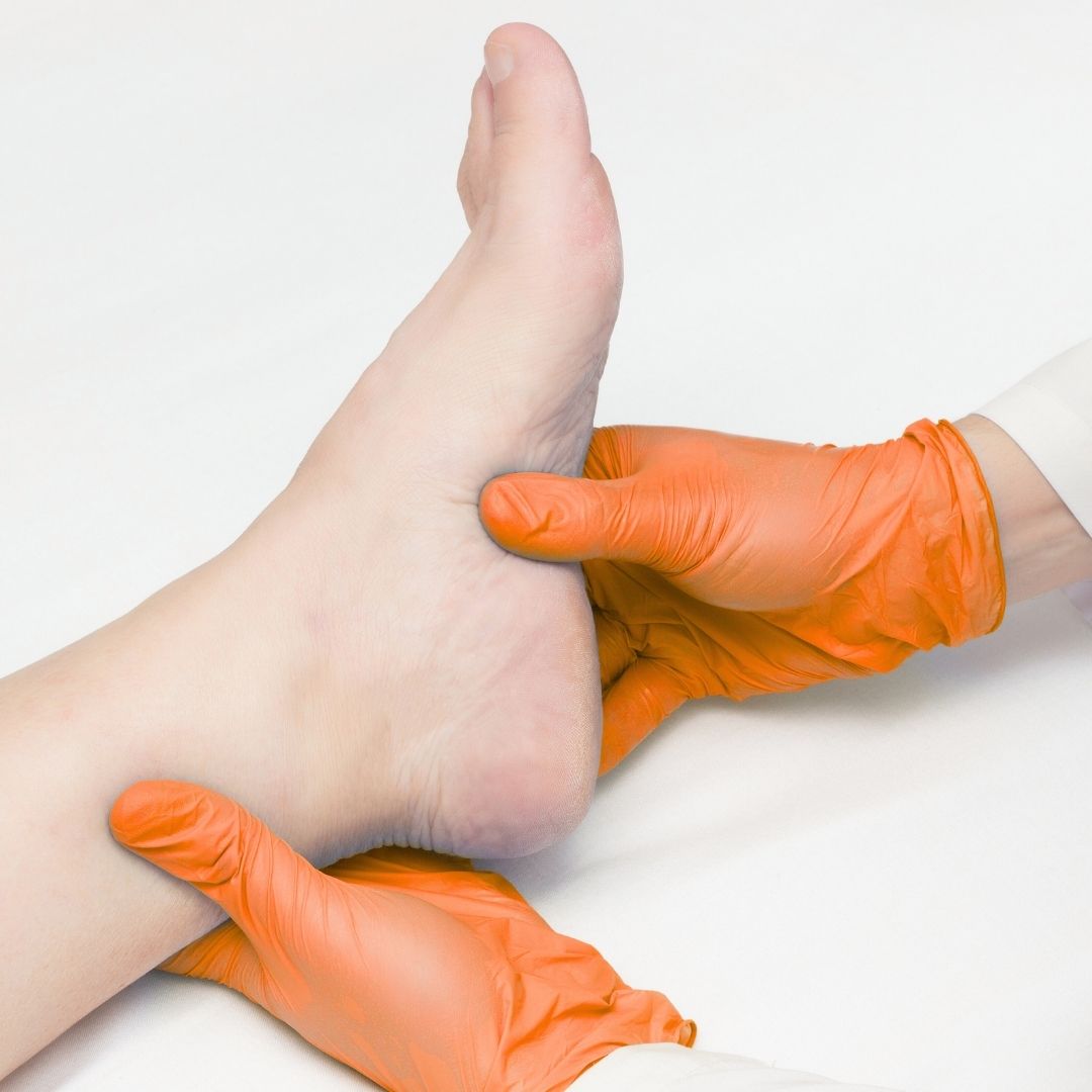Gloved hands gently holding a foot during a medical checkup.