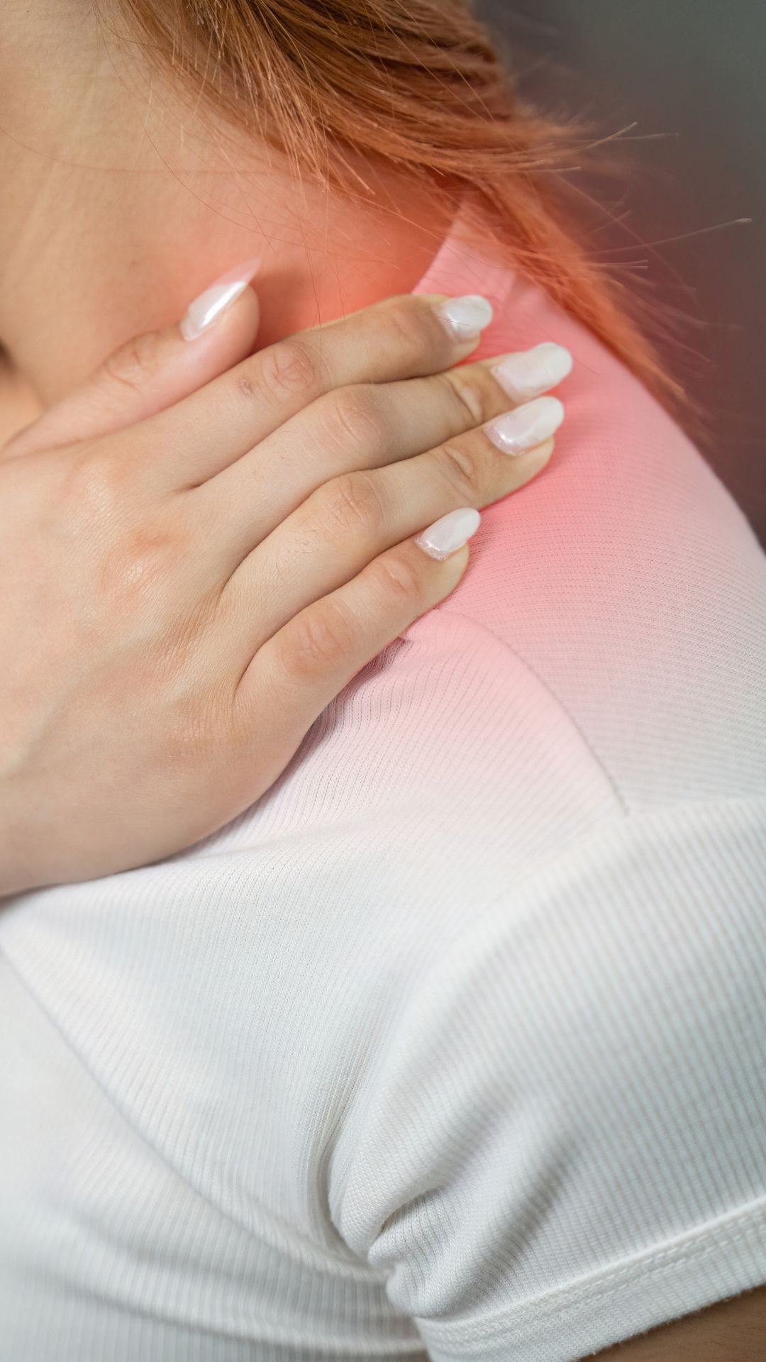 Close-up of a hand resting on a painful shoulder, with red glow indicating inflammation or discomfort.