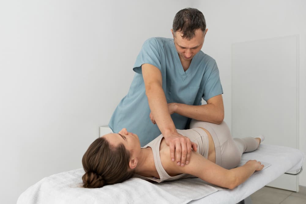 Chiropractor adjusting a patient's shoulder during a treatment session.